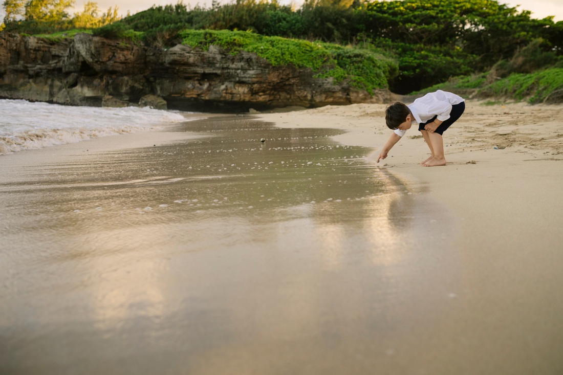 boy writing in the sand at laie beach