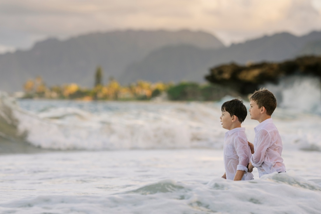 boys braving the big waves at pounders beach in laie after a family photo session