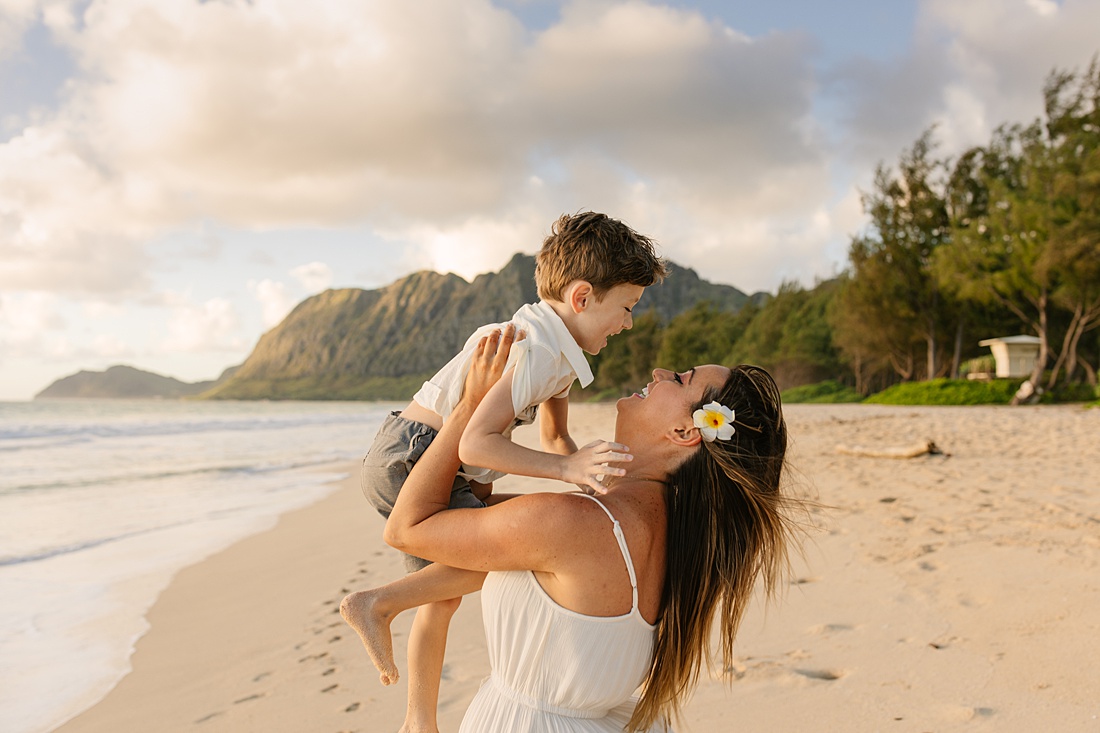Mom holding son in the air at a beach on oahu