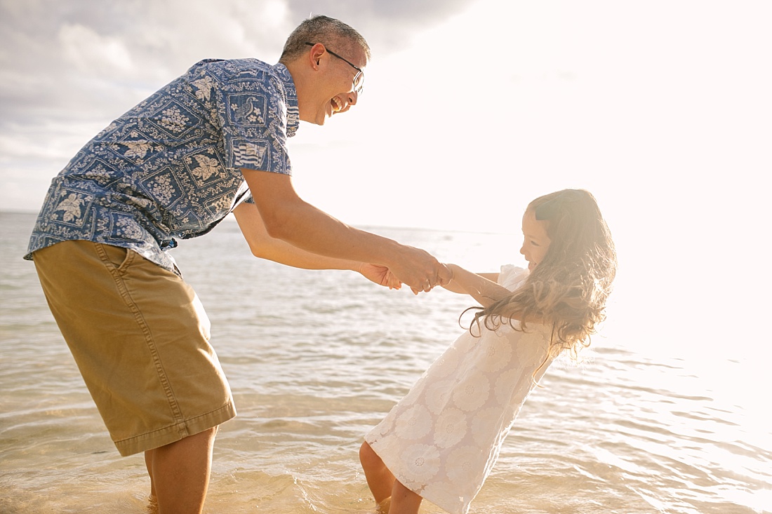 dad and daughter playing during a fun family portrait session at the beach in hawaii