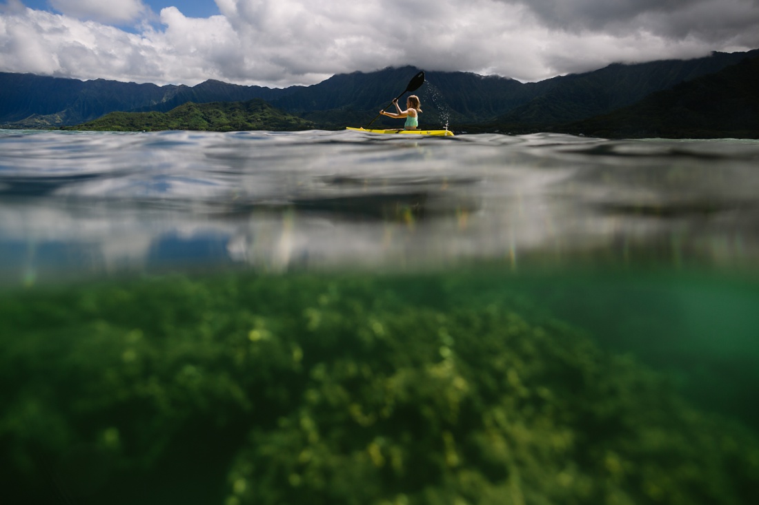 girl kayaking in kaneohe bay with views of coral below and mountains above by little bird photography