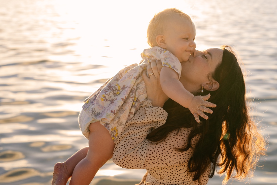 mom kissing baby at the beach