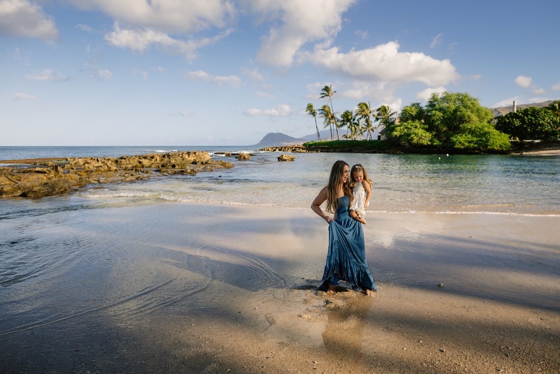 landscape with mom and daughter splashing in the shallows at koolina 