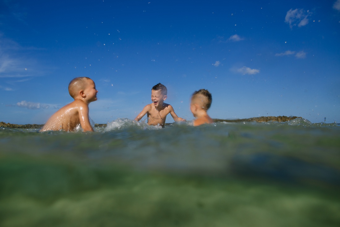 boys laughing and splashing in the water at paradise cove koolina