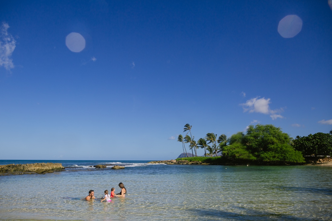 family splashing in the water at paradise cove in koolina oahu