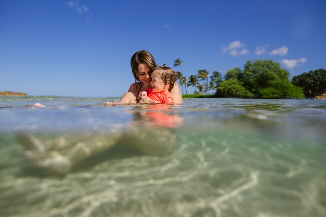 mom and toddler playing in the shallows during a family photoshoot in koolina