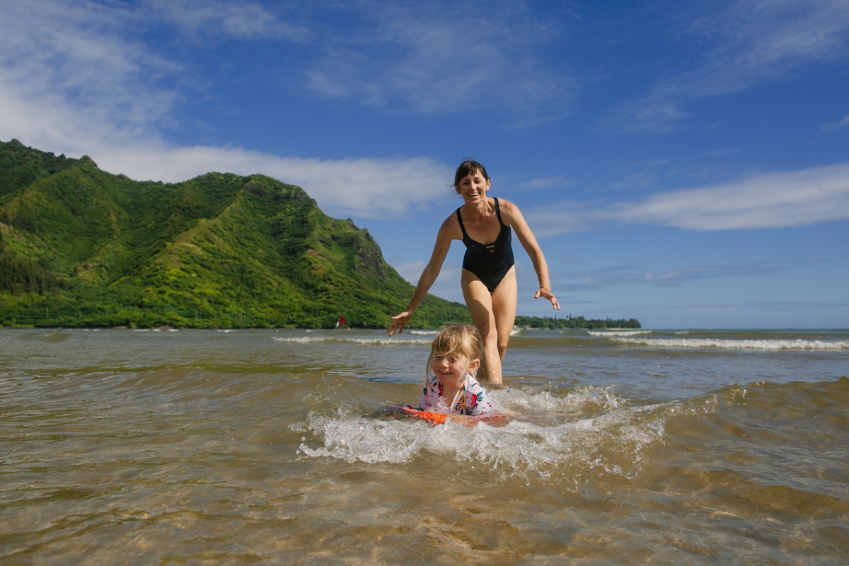 mom pushing daughter on a body board in oahu