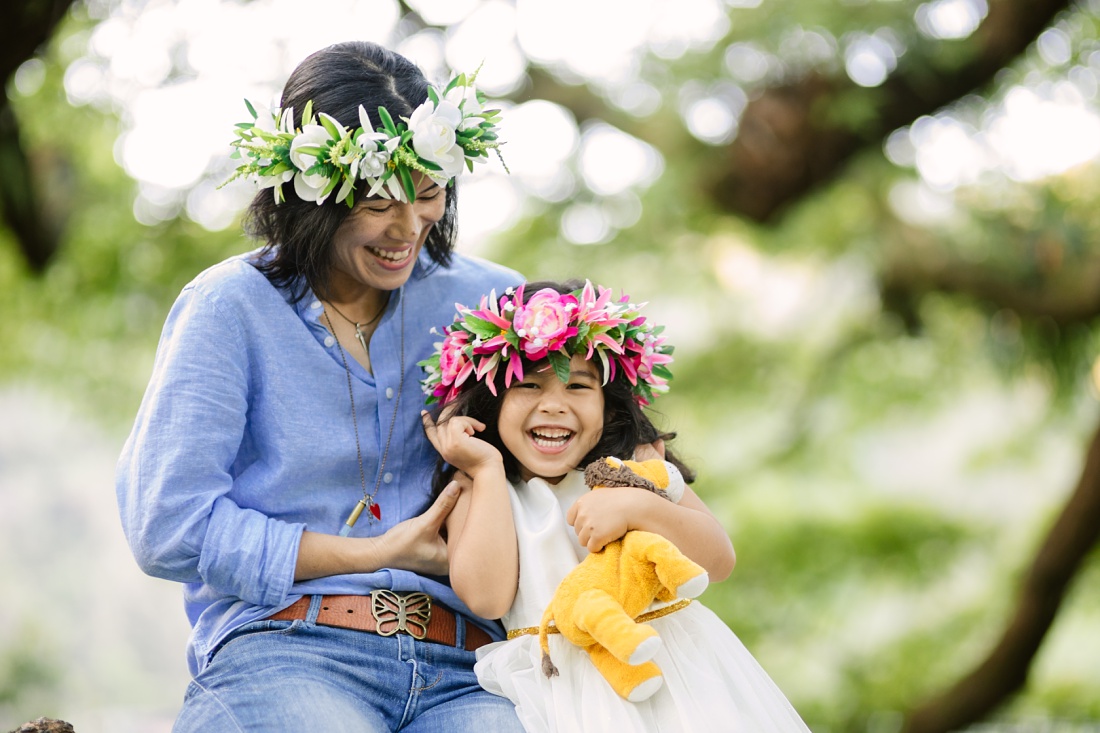 mom and daughter on a tree branch wearing haku lei in hawaii