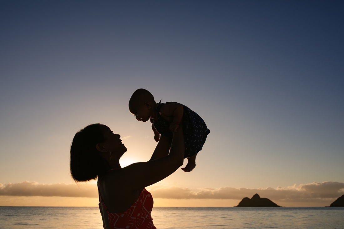 silhouette of mom holding baby in the air at sunrise on lanikai beach