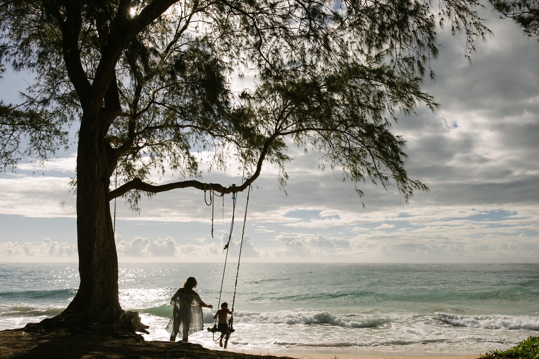 mom pushing her son on a tree swing in hawaii during a family photography session