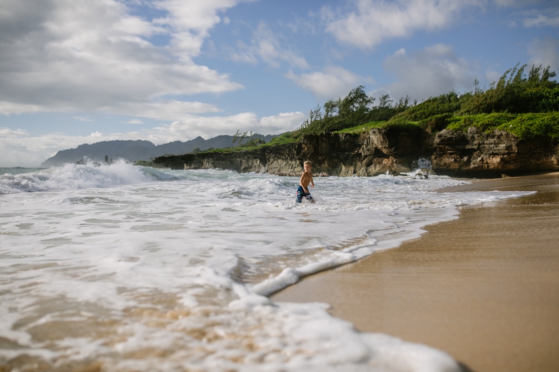 boy playing in the surf at laie beach park oahu by little bird photography