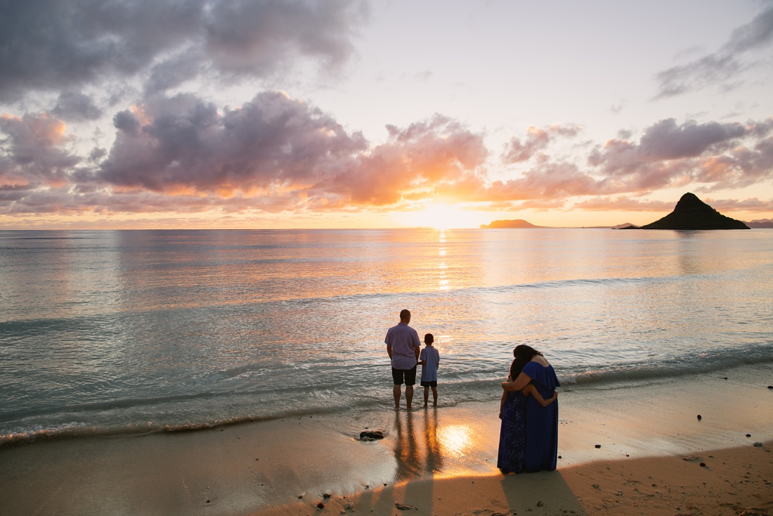 family watching the sun rise over the beach during Sunrise Family Portraits on Oahu