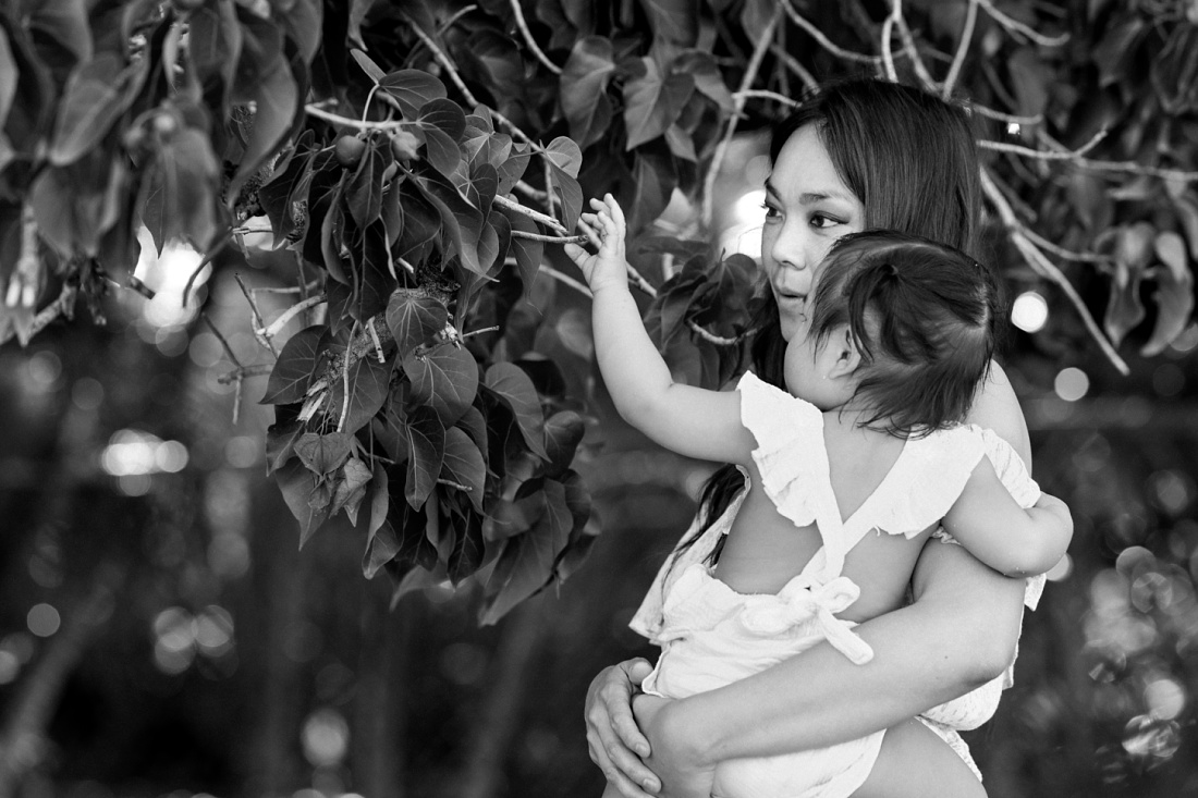 b&w photo of mom and baby looking for flowers in hawaii