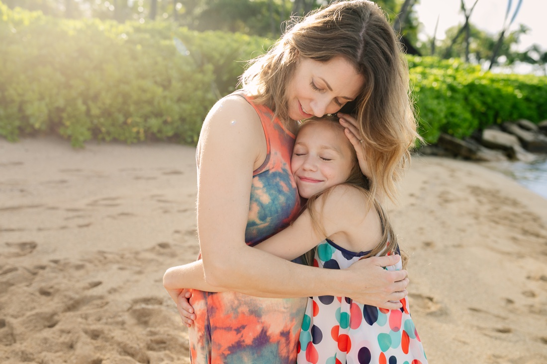mom and daughter hugging on the beach in koolina by little bird photography