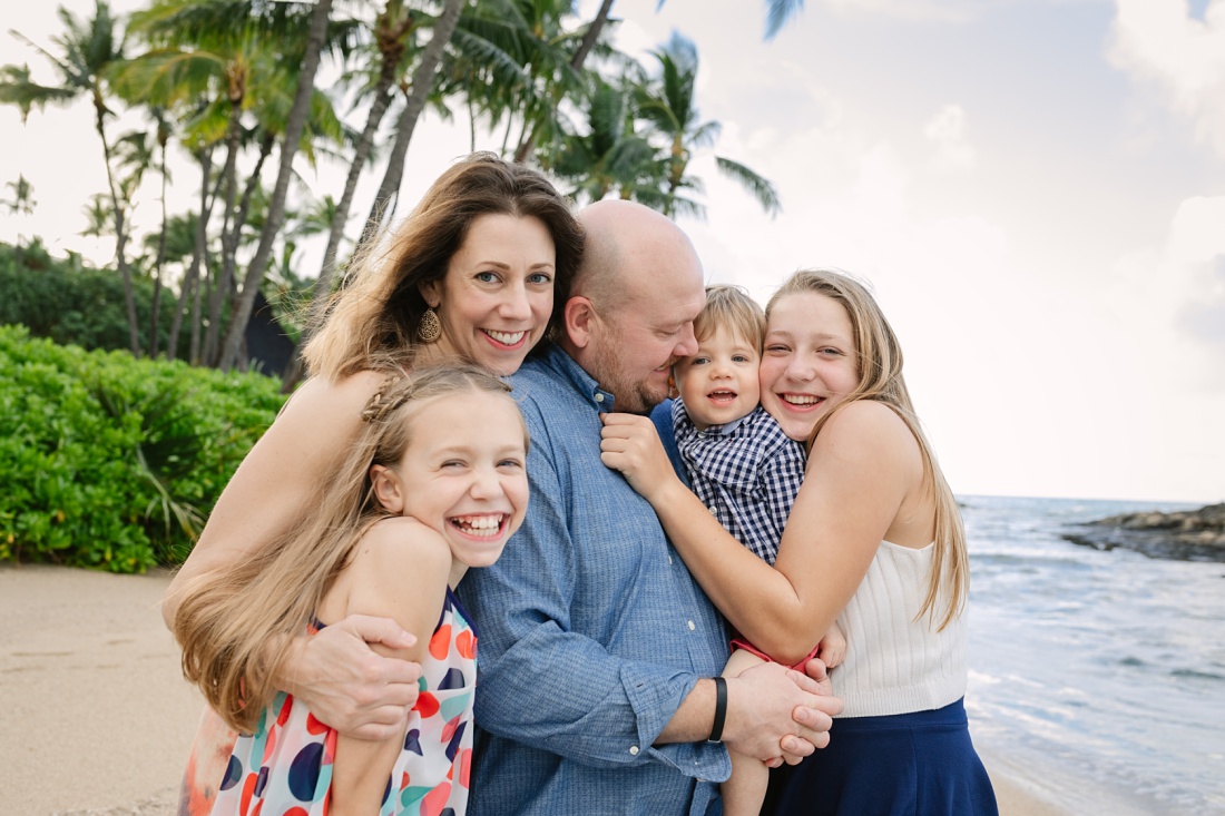 a family hug portrait at the beach in hawaii