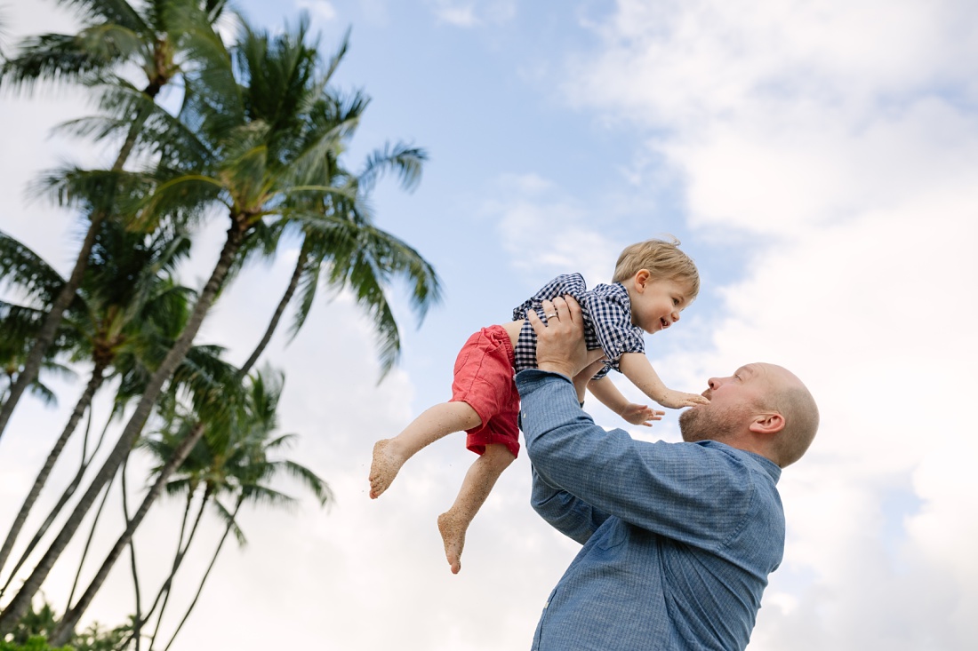 dad tossing son in the air during a beach photo shoot