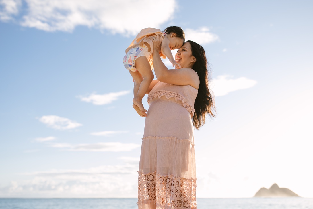 mom and toddler daughter play at lanikai beach during a photo session