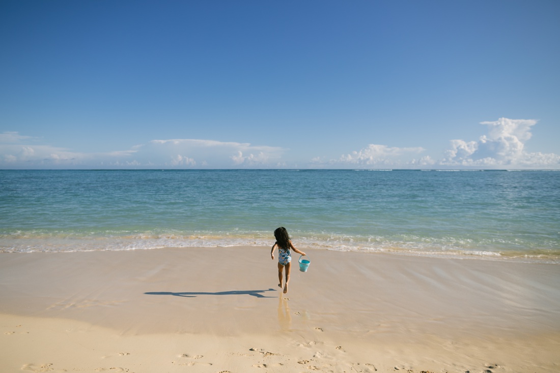girl running to get water at lanikai beach kailua during a fun photo session