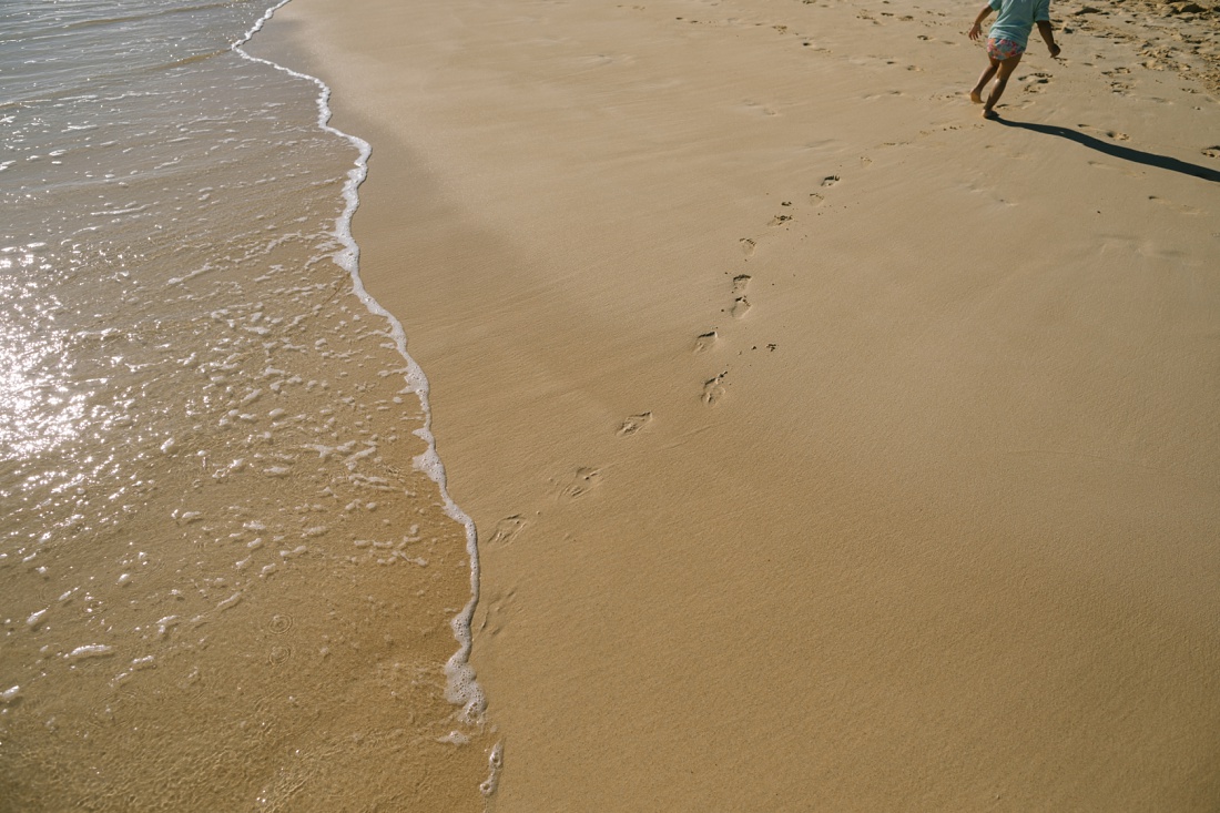 toddler and footprints in the sand in kailua oahu
