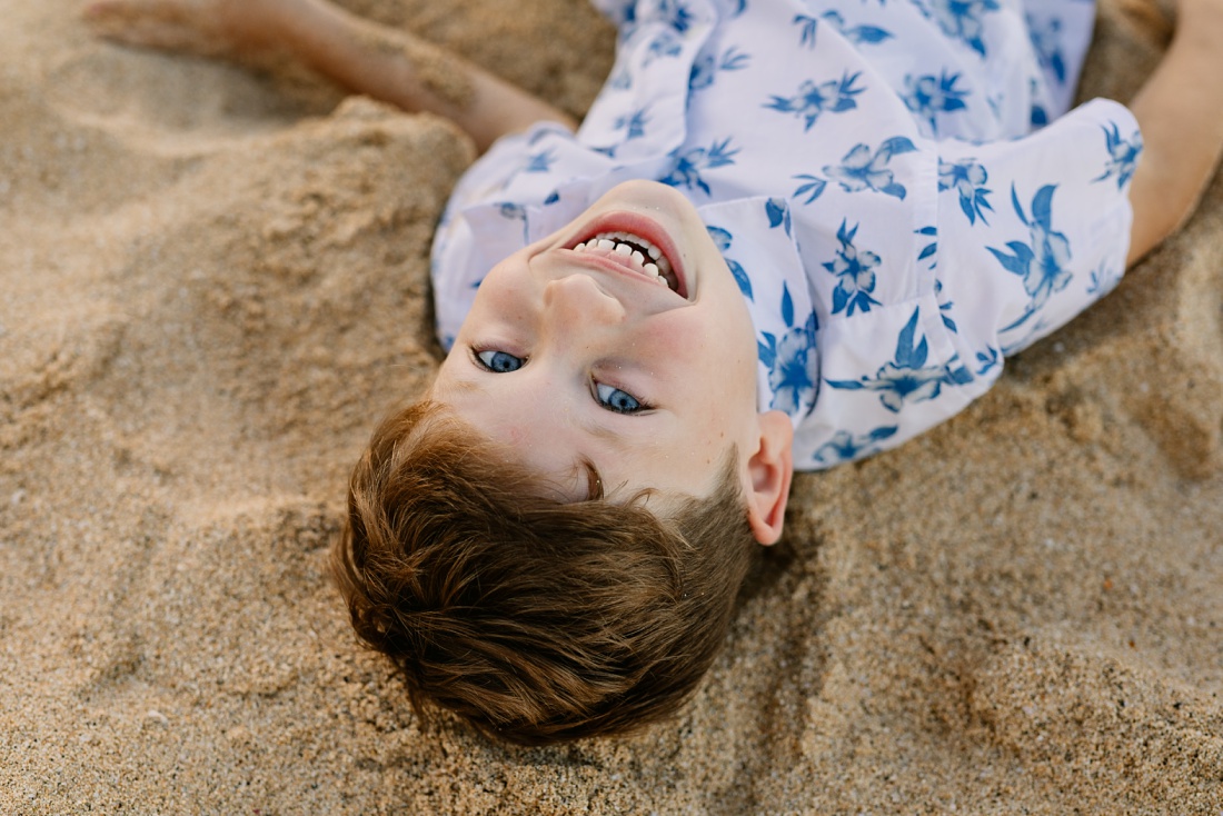 portrait of a boy lying in the sand