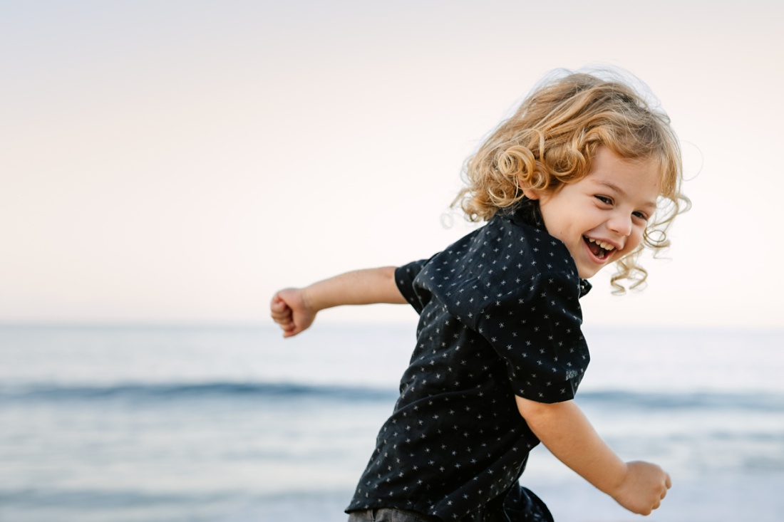 curly haired toddler running on the beach