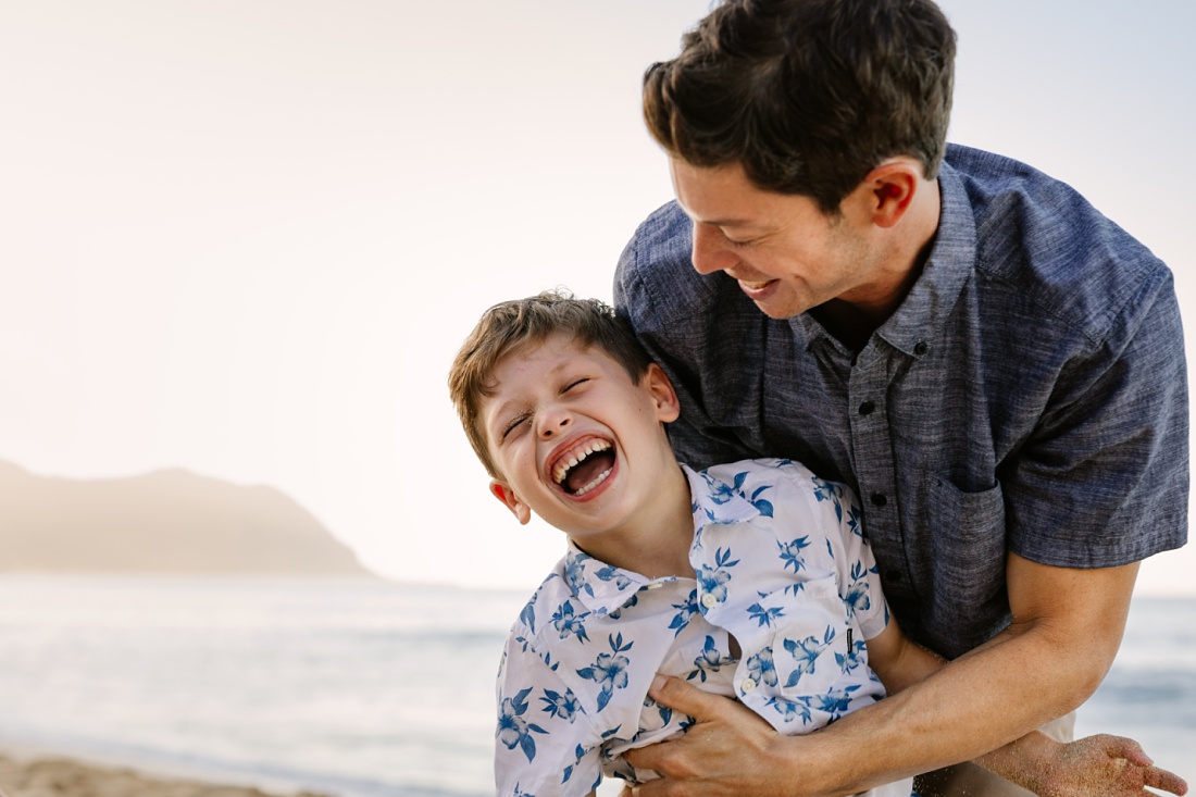 dad tickling son at the beach during a family portrait session