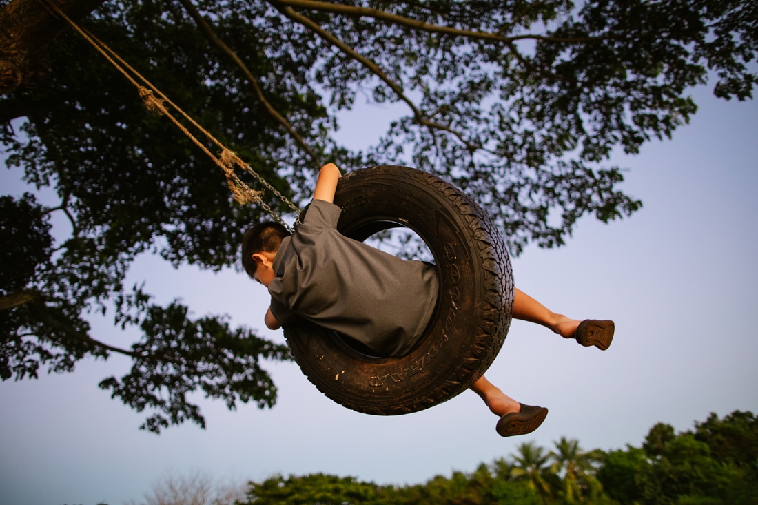 boy on a tire swing in hawaii