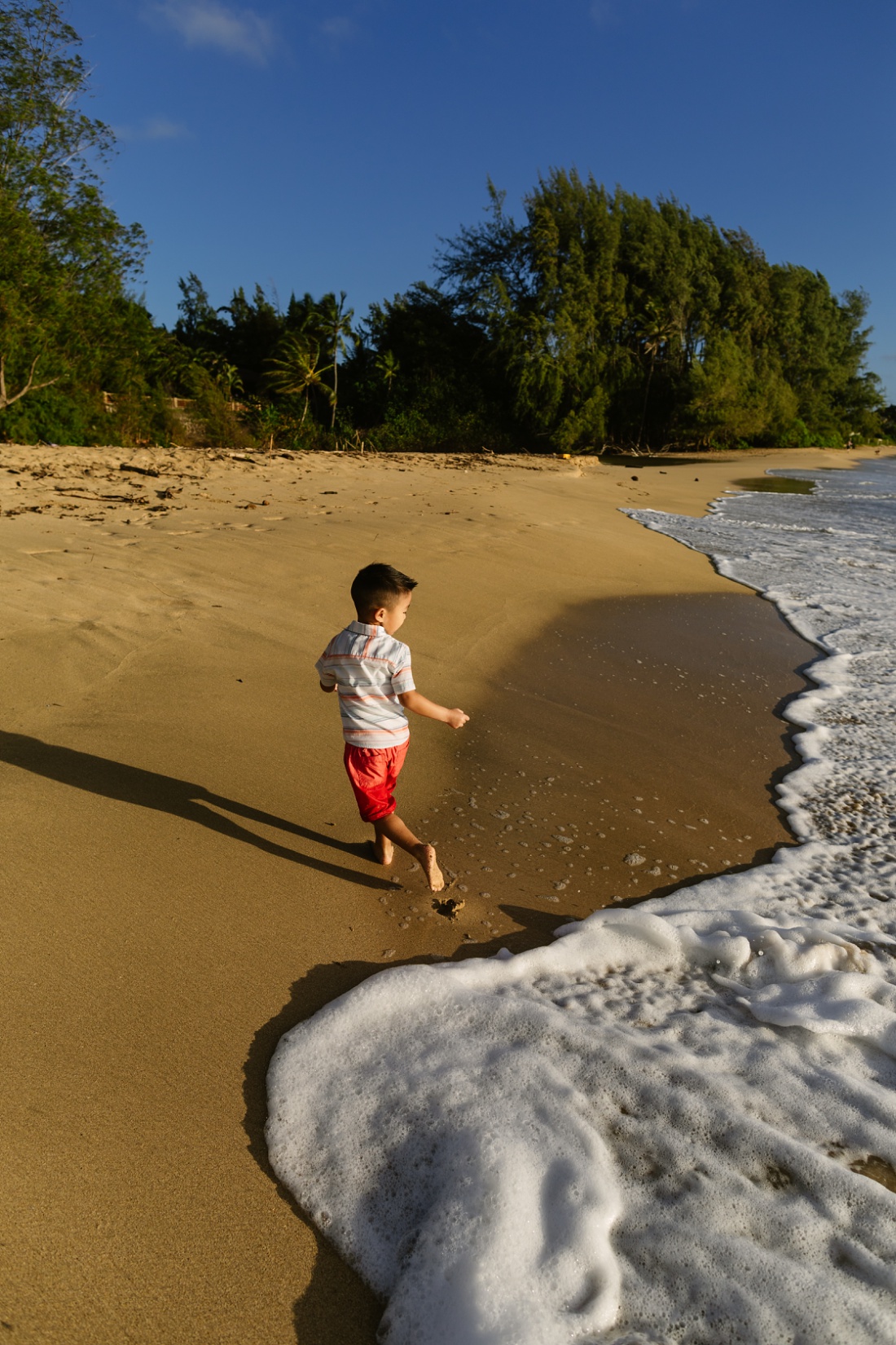 boy running from the waves at laie beach by little bird photography