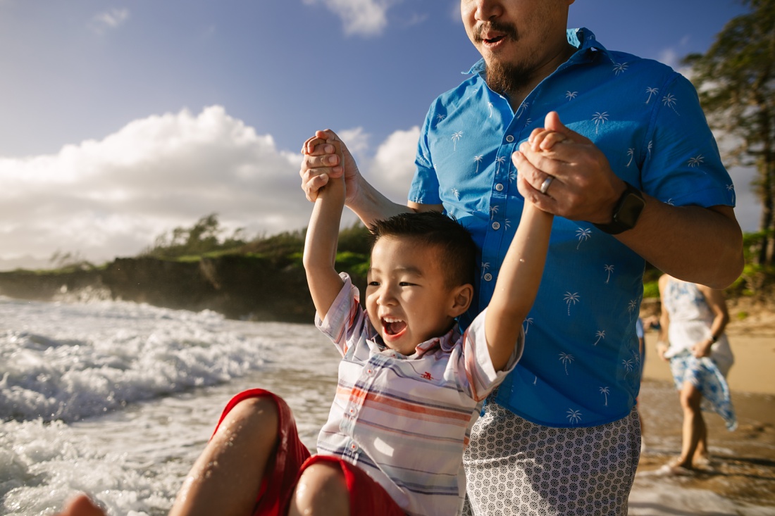dad and son play in the waves in laie