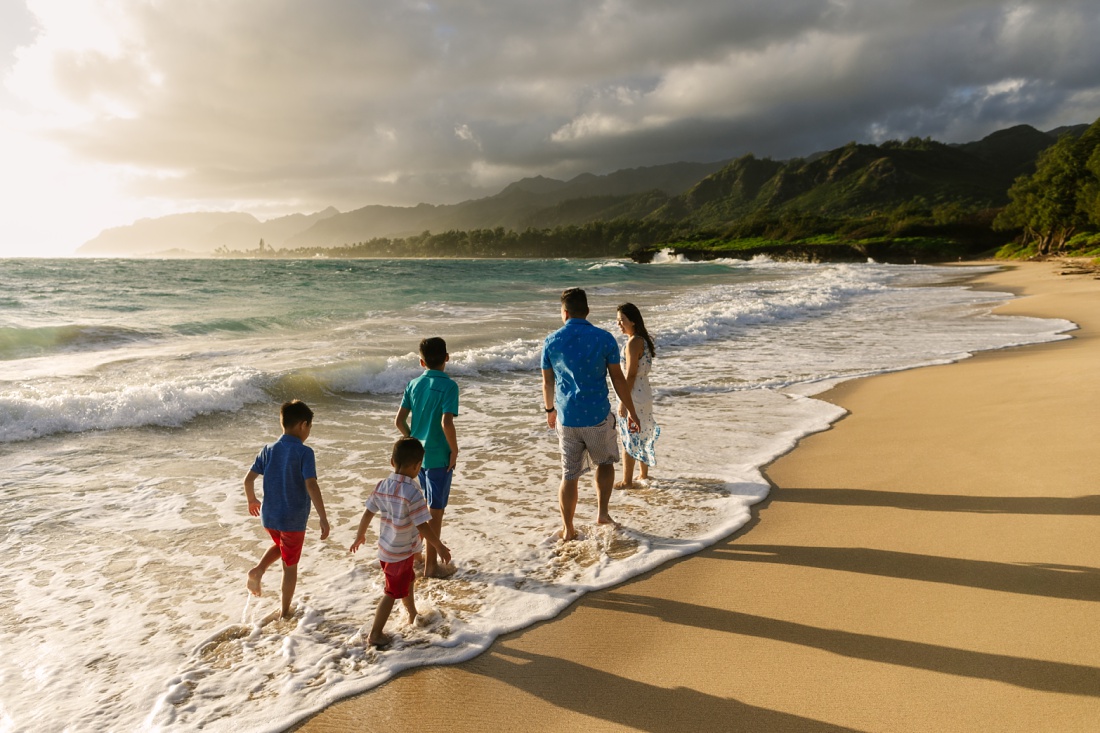 family walking along the shore at laie beach in oahu