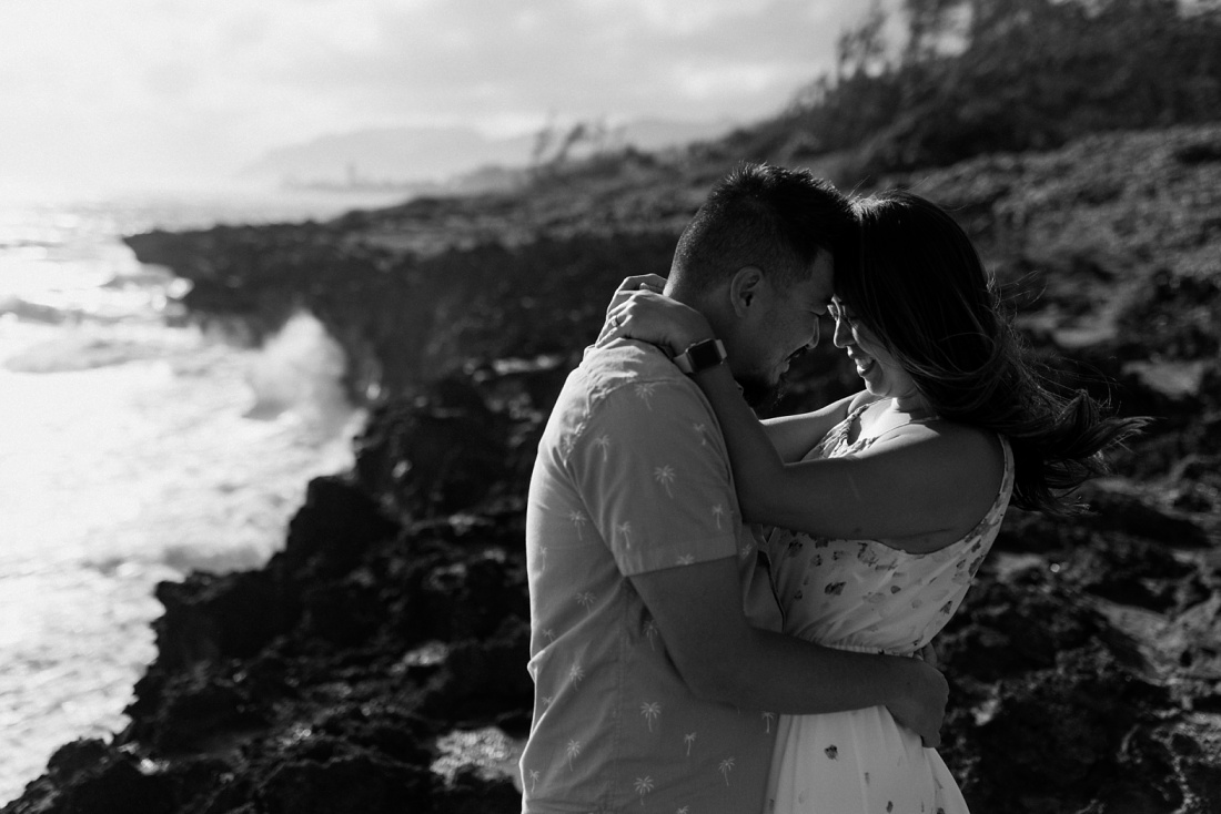 couple snuggles against the backdrop of laie beach during a family photography session