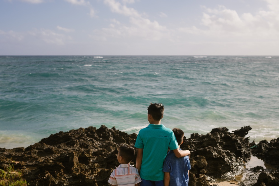brothers look out at a rough ocean from laie cliffs