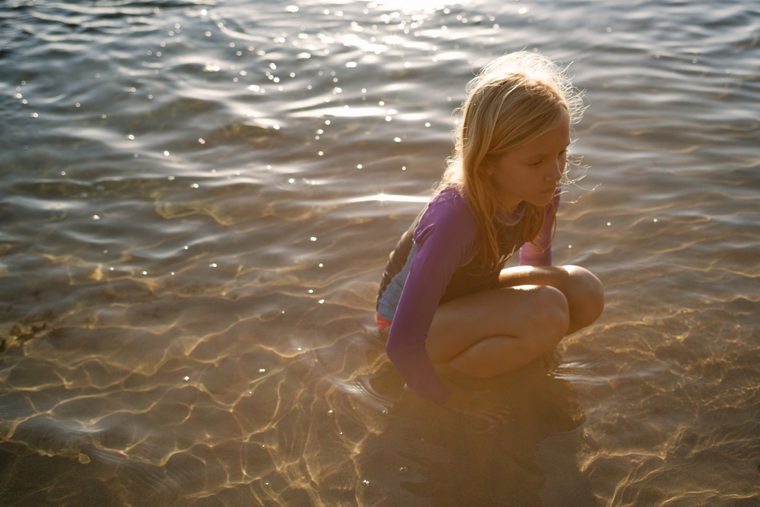 girl in the water with sunflare