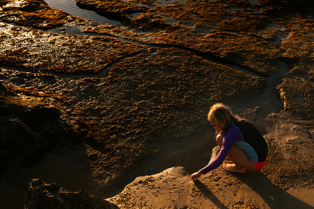 girl searching the tide pool at sunset in hawaii
