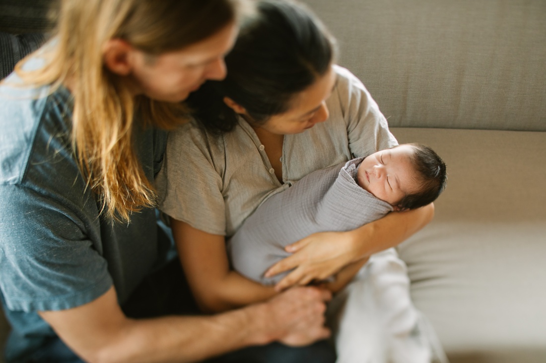 mom and dad snuggle their wrapped newborn during a family photo session