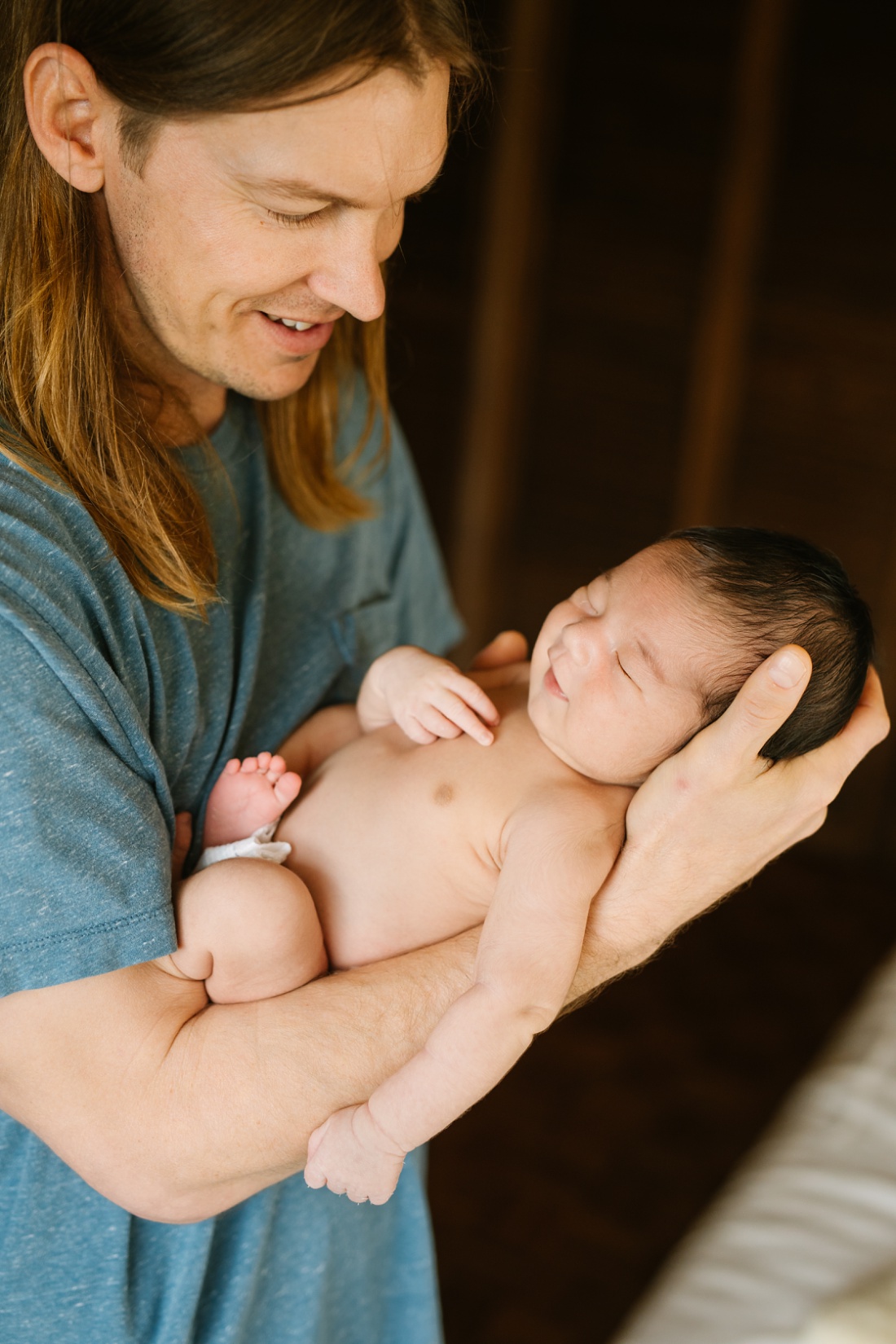 newborn baby smiles as dad holds him during a newborn photography session at home