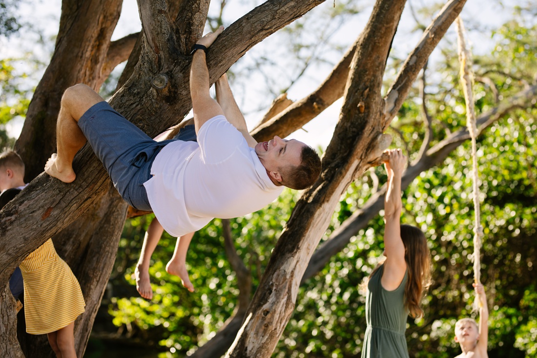 dad hanging from a tree during a fun photo session in hawaii