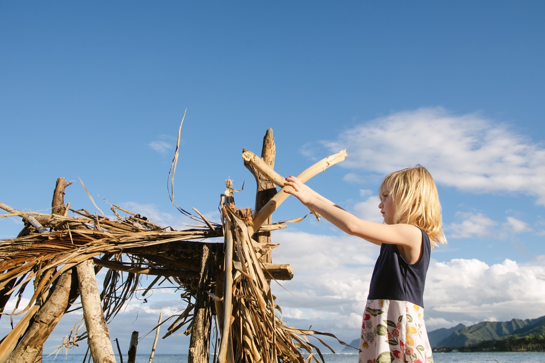 girl builds a driftwood fort at pounders beach oahu