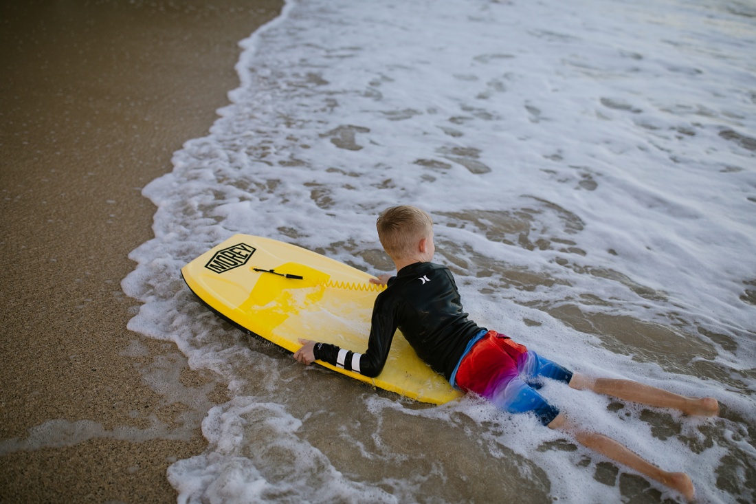 boy catches a wave into shore on his yellow bodyboard