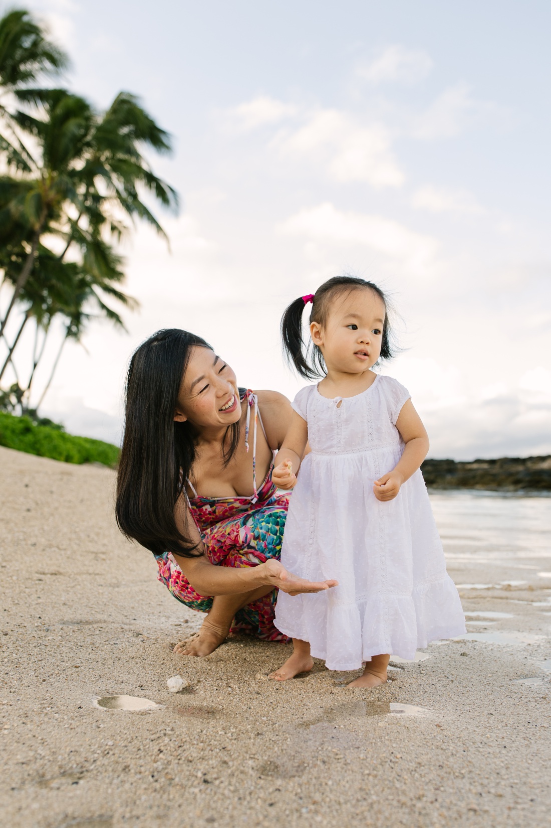 mom and toddler daughter portrait of her first time at the beach in hawaii