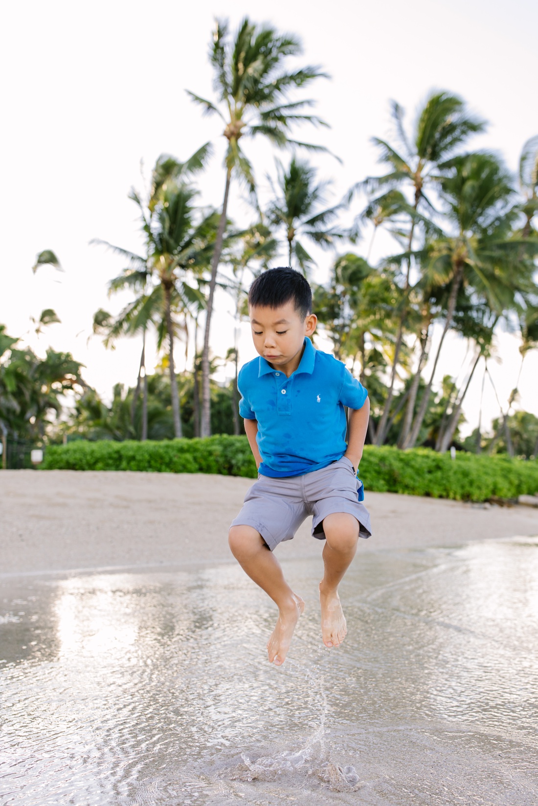 boy jumping in the shallows during a family photoshoot in oahu
