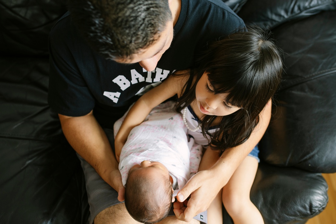 aerial view of dad and older daughter holding new baby at home
