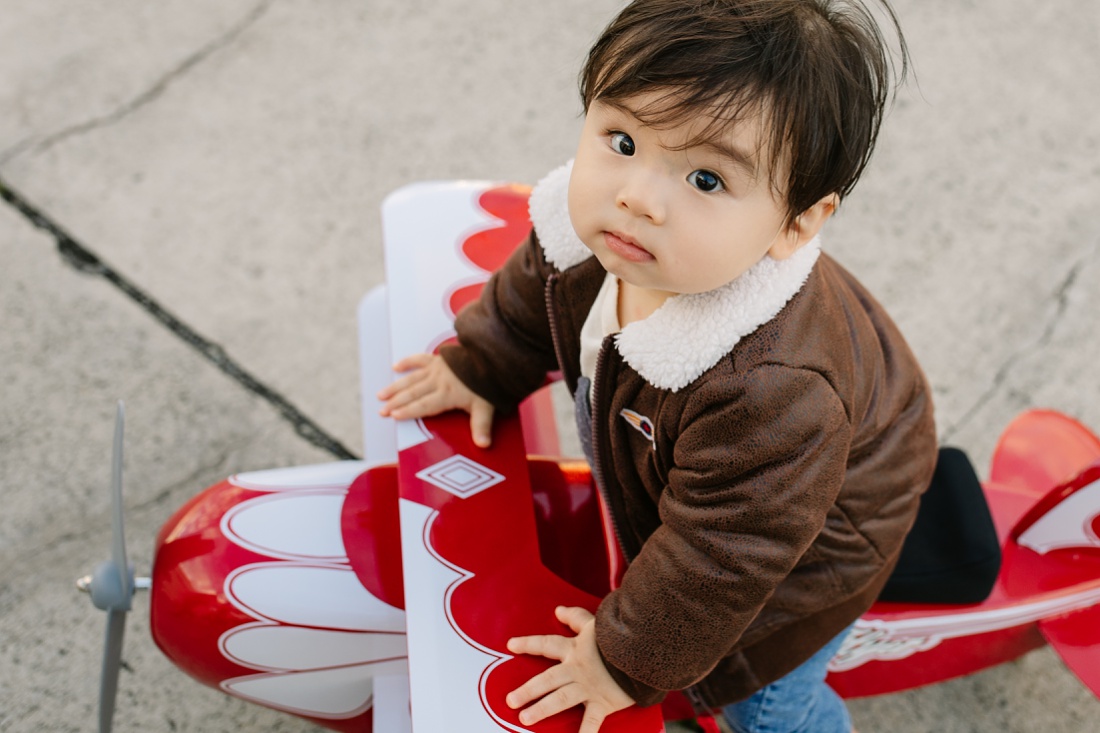 toddler with a bomber jacket in an airplane for his first birthday party