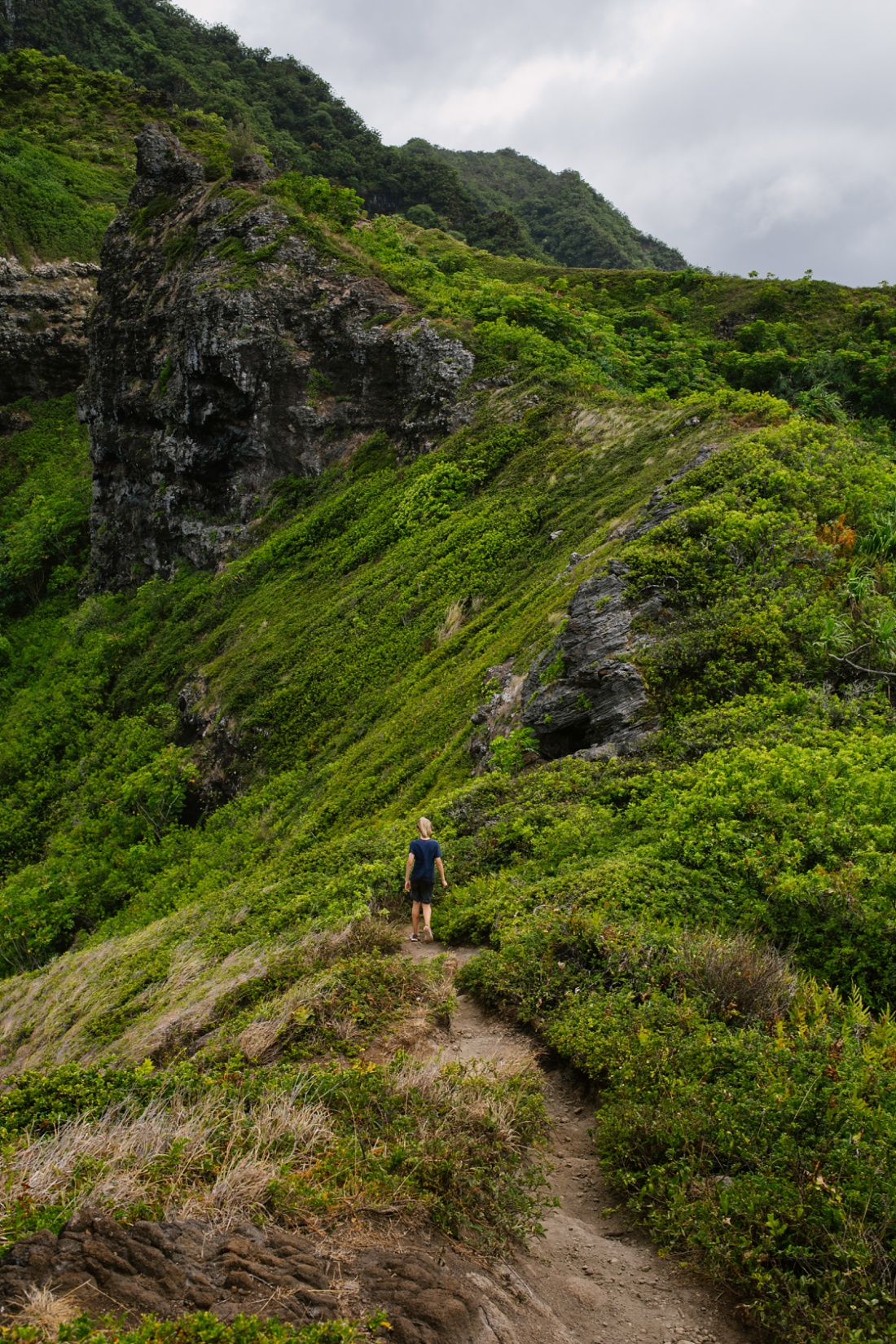 boy hikes along the steep ridgeline in Kahana, windward Oahu