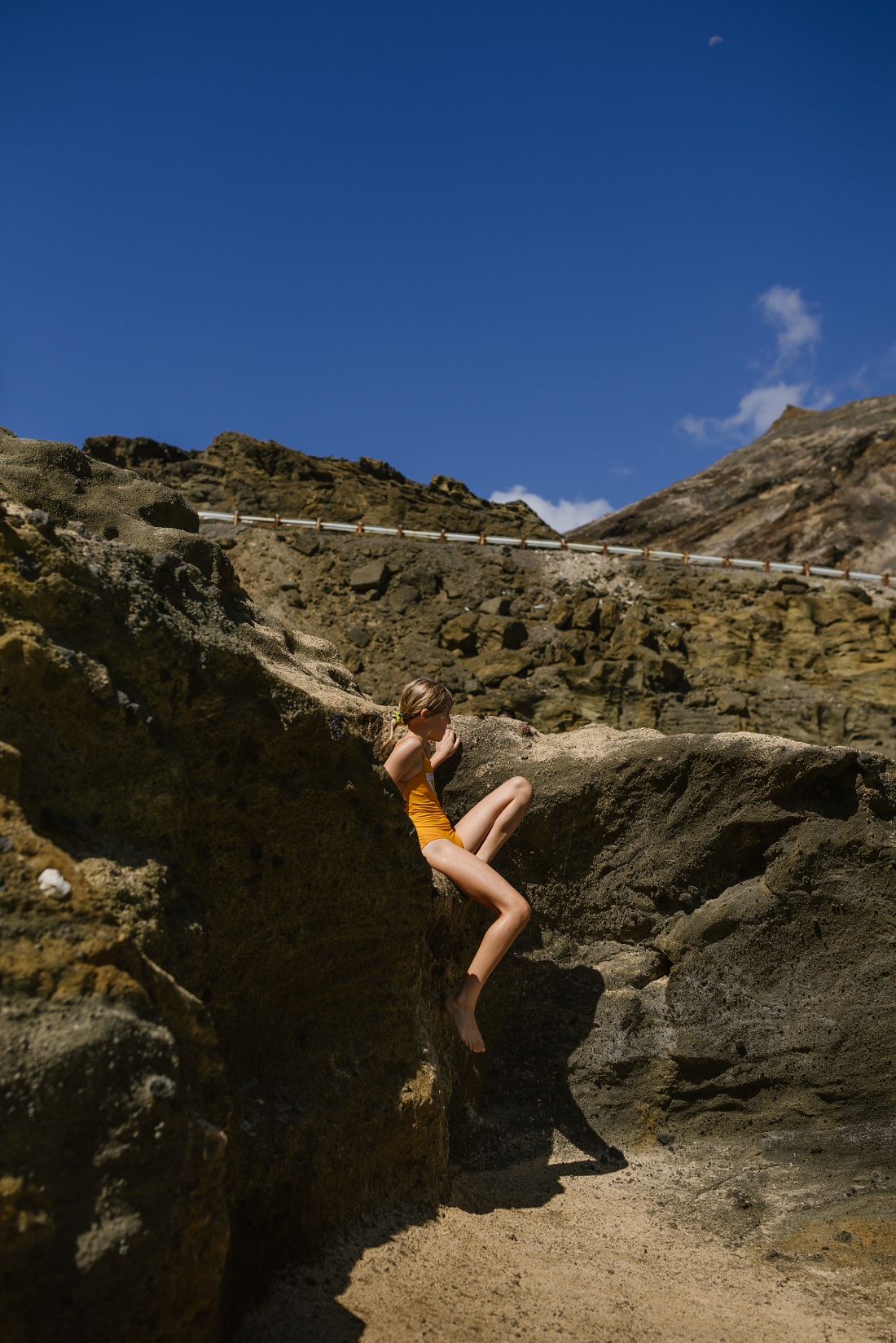 girl climbing the rocks at halona beach cove during a family photo session in oahu