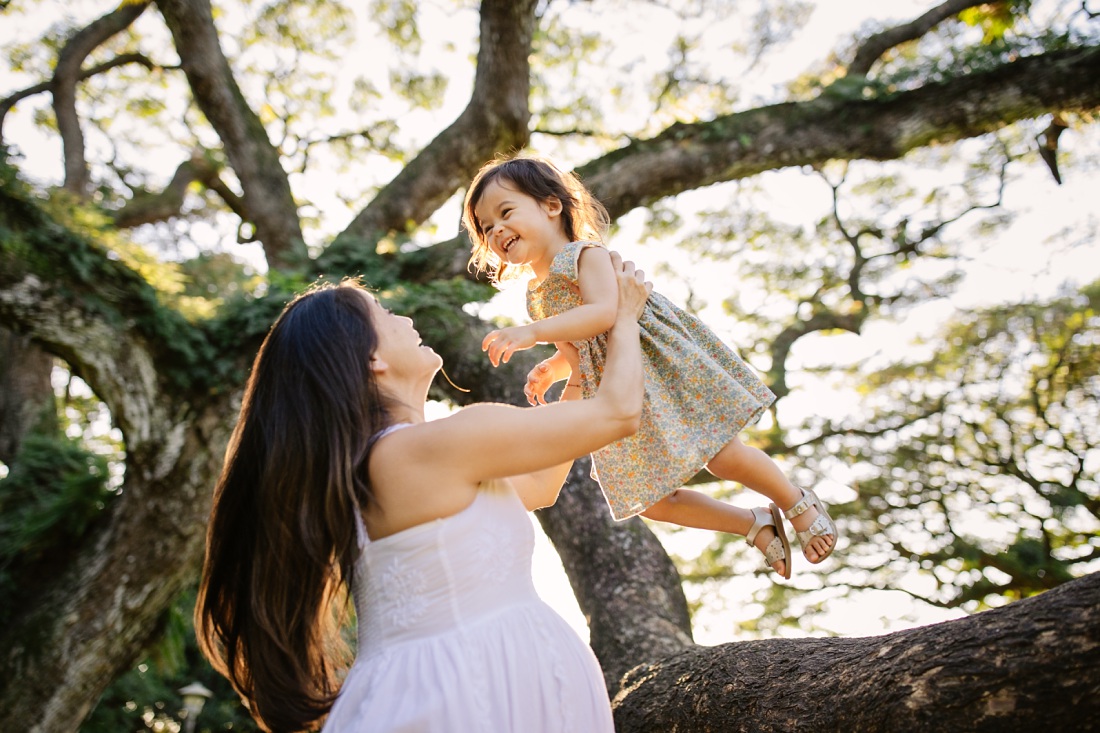 toddler girl jumping into moms arms during a maternity photo session in oahu