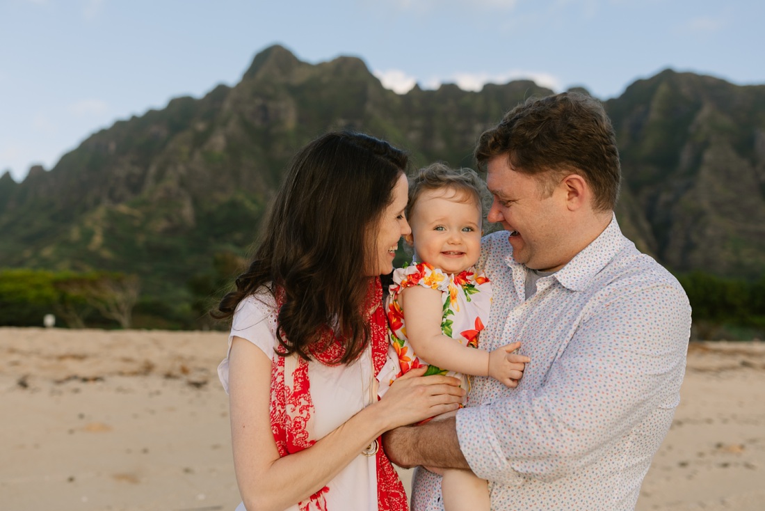 a family of 3 shares a hug at kualoa during a family photo shoot by little bird photography