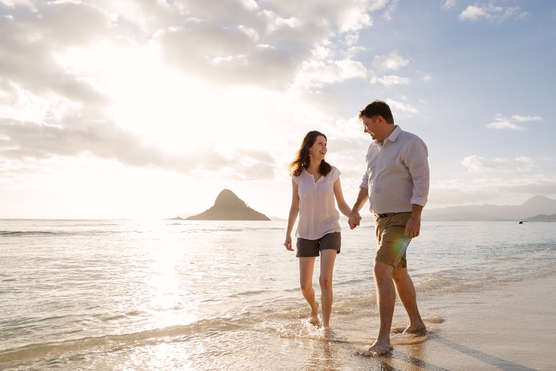 a happy couple walking on a beach in hawaii at sunrise