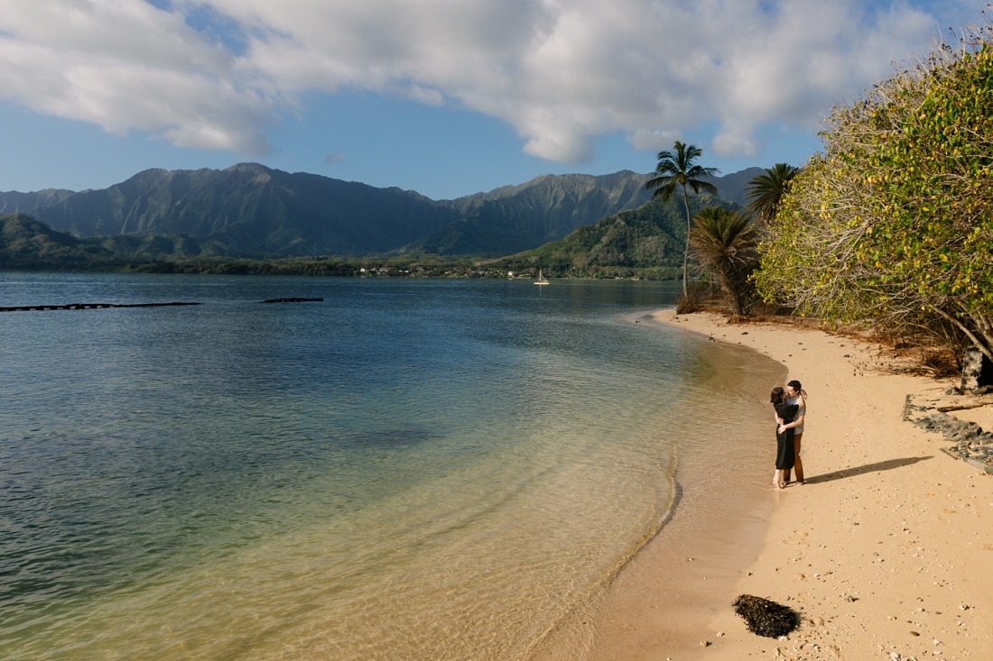 couple kisses on an empty beach in kualoa oahu hawaii
