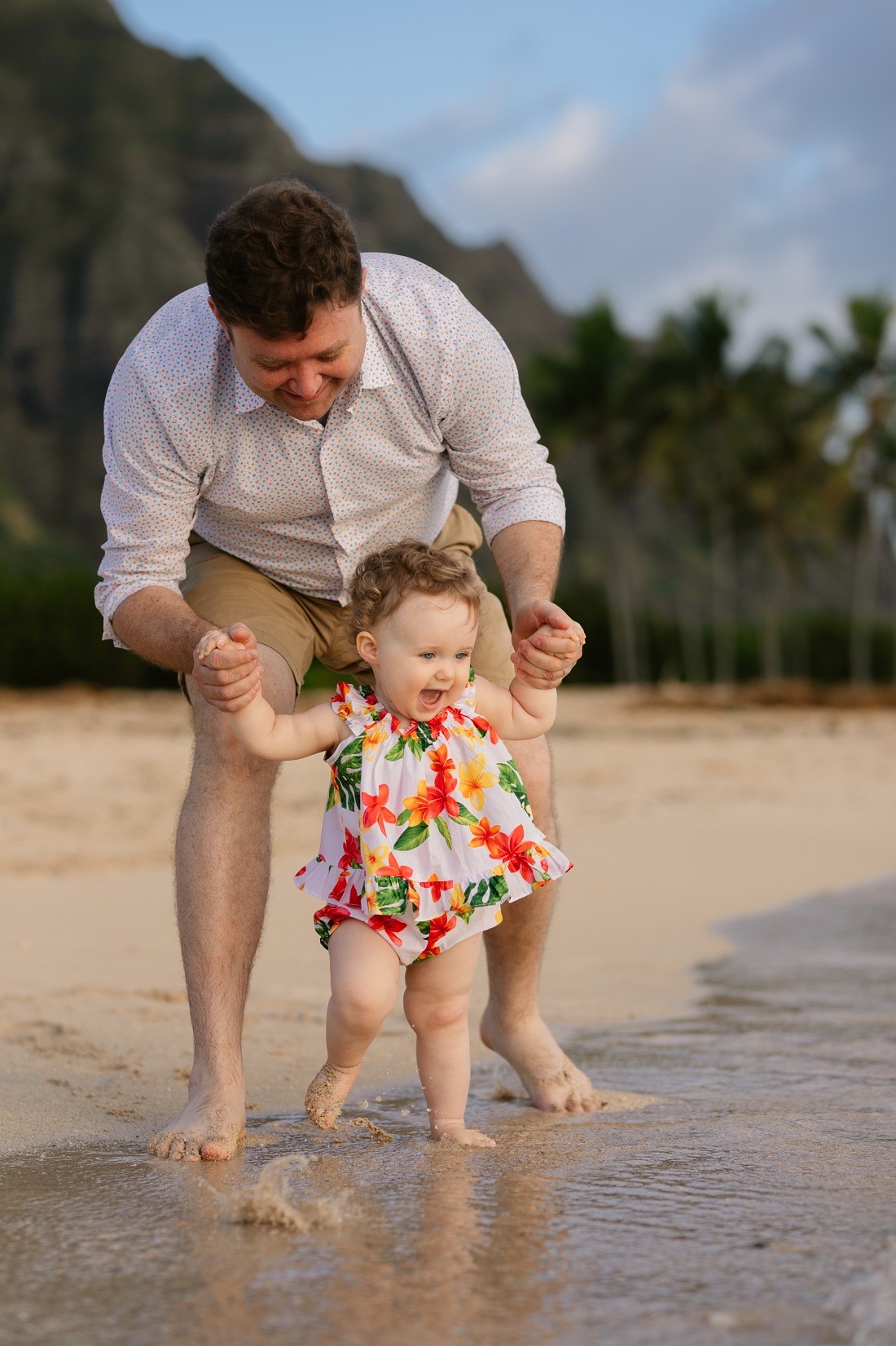 dad and happy baby splashing in the waves on shore at kualoa beach park